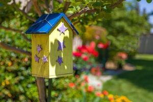 Yellow bird feeder with purple stars on exterior and blue roof